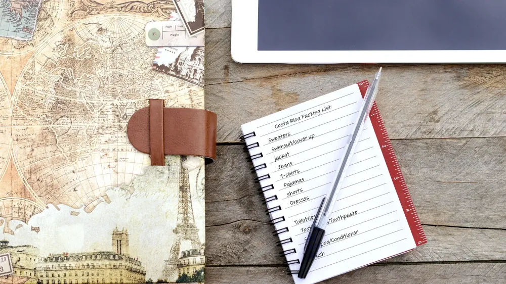 packing list written in a notebook on a table.